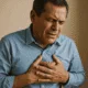 Man experiencing chest pain, holding his chest with a distressed expression, indicating possible heart-related issues